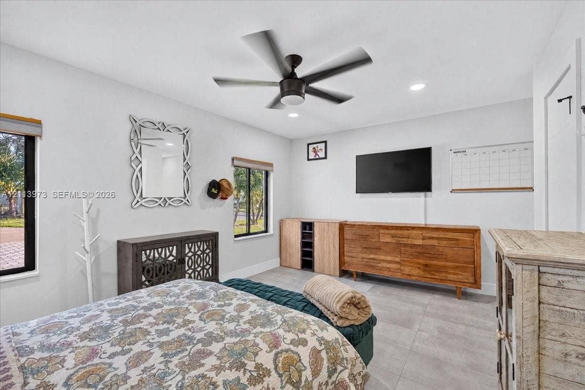 Neutral-toned tile flooring, recessed ceiling lighting, and a multi-blade matte black ceiling fan