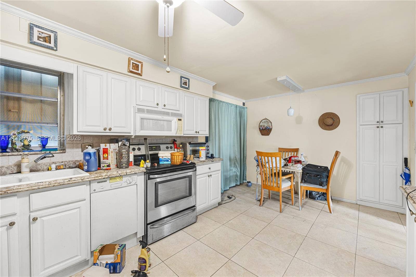 3740 NE 6th Avenue, Oakland Park, FL 33334 Kitchen featuring white cabinetry, stone-finish countertops, stainless steel appliances, ceramic tile flooring, and a built-in pantry