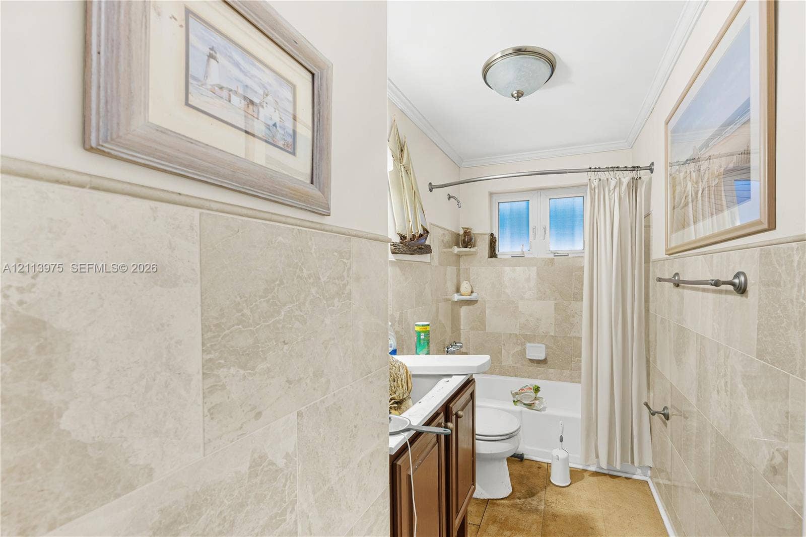 3740 NE 6th Avenue, Oakland Park, FL 33334 Full-height stone wall tiling with matching crown molding, wood-finish cabinetry, and built-in recessed wall shelving