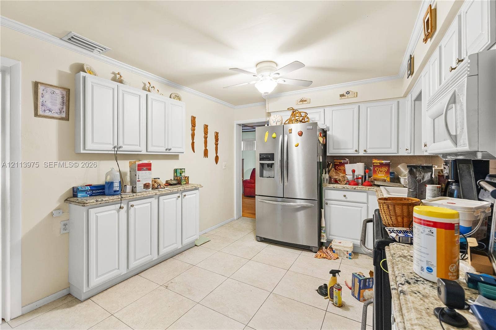 3740 NE 6th Avenue, Oakland Park, FL 33334 Kitchen featuring white cabinetry, stone-finish countertops, tile flooring, stainless steel French door refrigerator, and built-in microwave