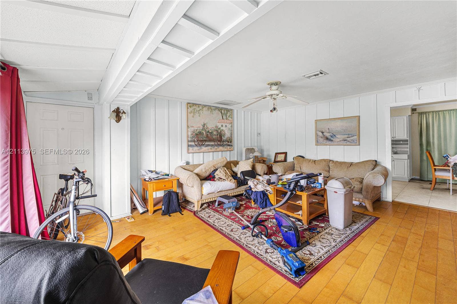 3740 NE 6th Avenue, Oakland Park, FL 33334 Interior featuring wood-finish flooring, vertical plank wall paneling, and a ceiling-mounted fan
