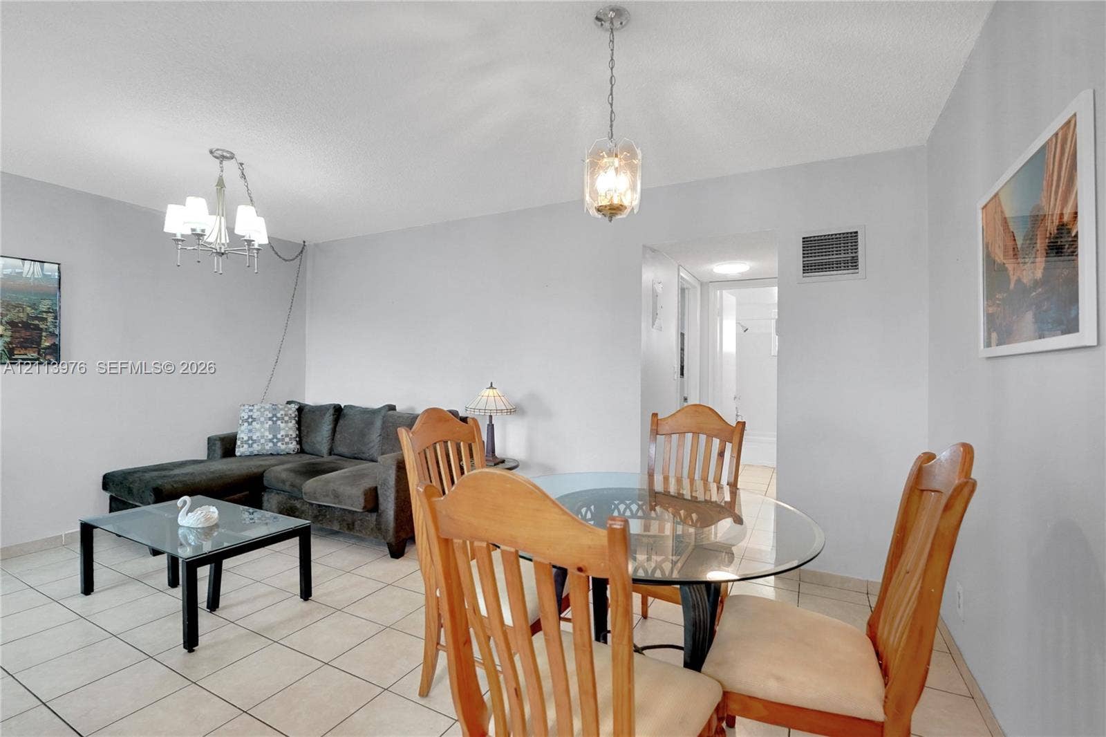 2145 Pierce Street, #416, Hollywood, FL 33020 Neutral-toned interior space featuring light-colored ceramic tile flooring, a multi-arm metallic chandelier, a decorative pendant light, and crisp neutral wall paint