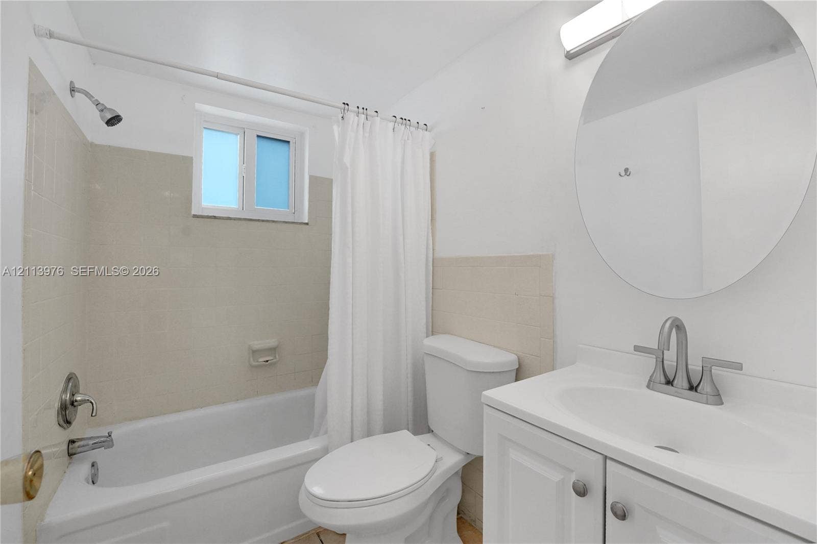 2145 Pierce Street, #416, Hollywood, FL 33020 Bathroom featuring a white vanity cabinet with a integrated sink, brushed-nickel faucet, circular wall-mounted mirror, and a tub-shower combination with tile surround
