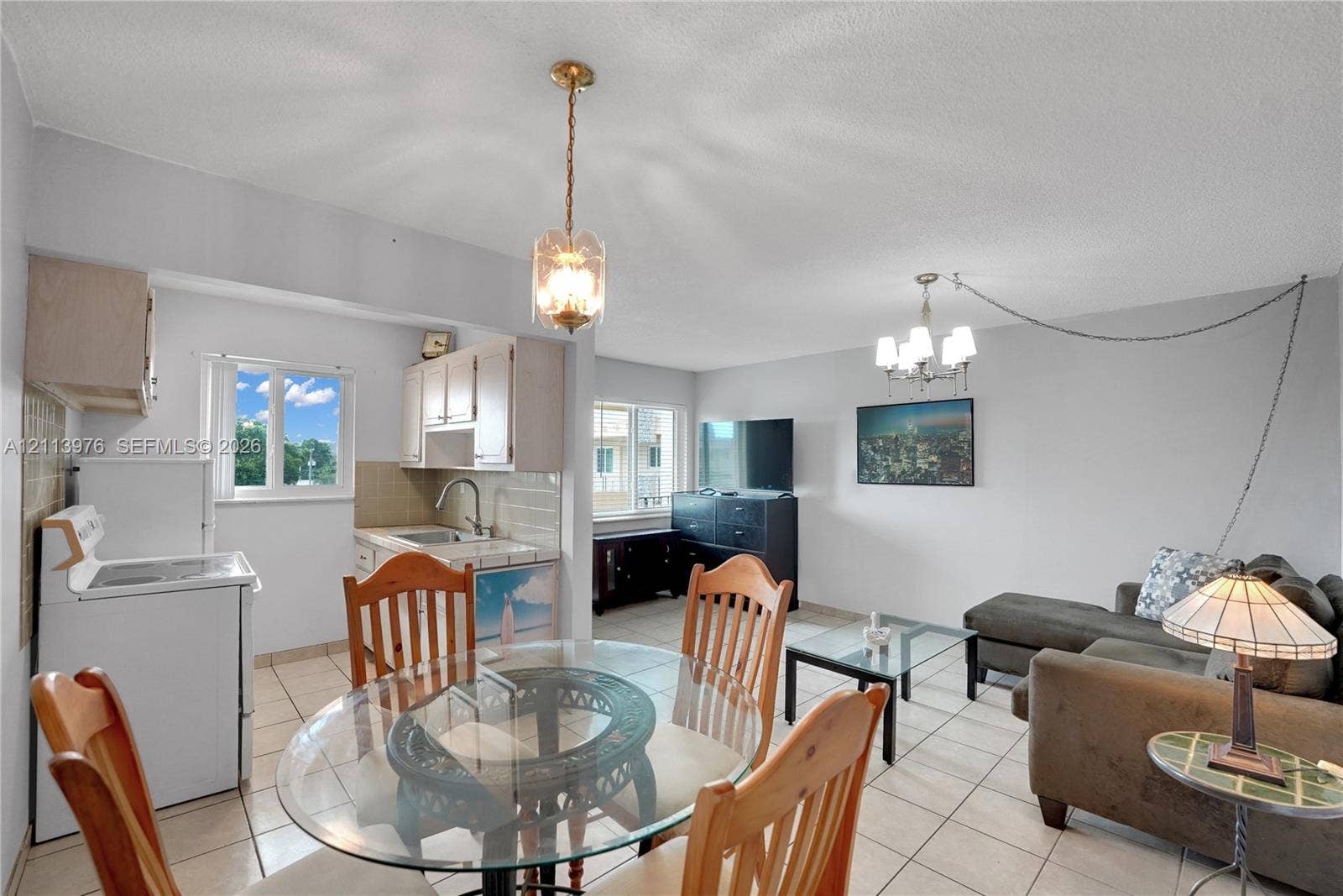 2145 Pierce Street, #416, Hollywood, FL 33020 Open-concept interior featuring large-format tile flooring, dual hanging pendant light fixtures, and windows providing natural light