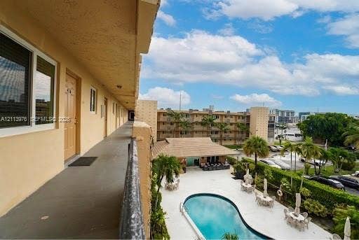 2145 Pierce Street, #416, Hollywood, FL 33020 Exterior walkway featuring a concrete floor surface and a protective metal railing, overlooking an outdoor swimming pool with a surrounding paved deck