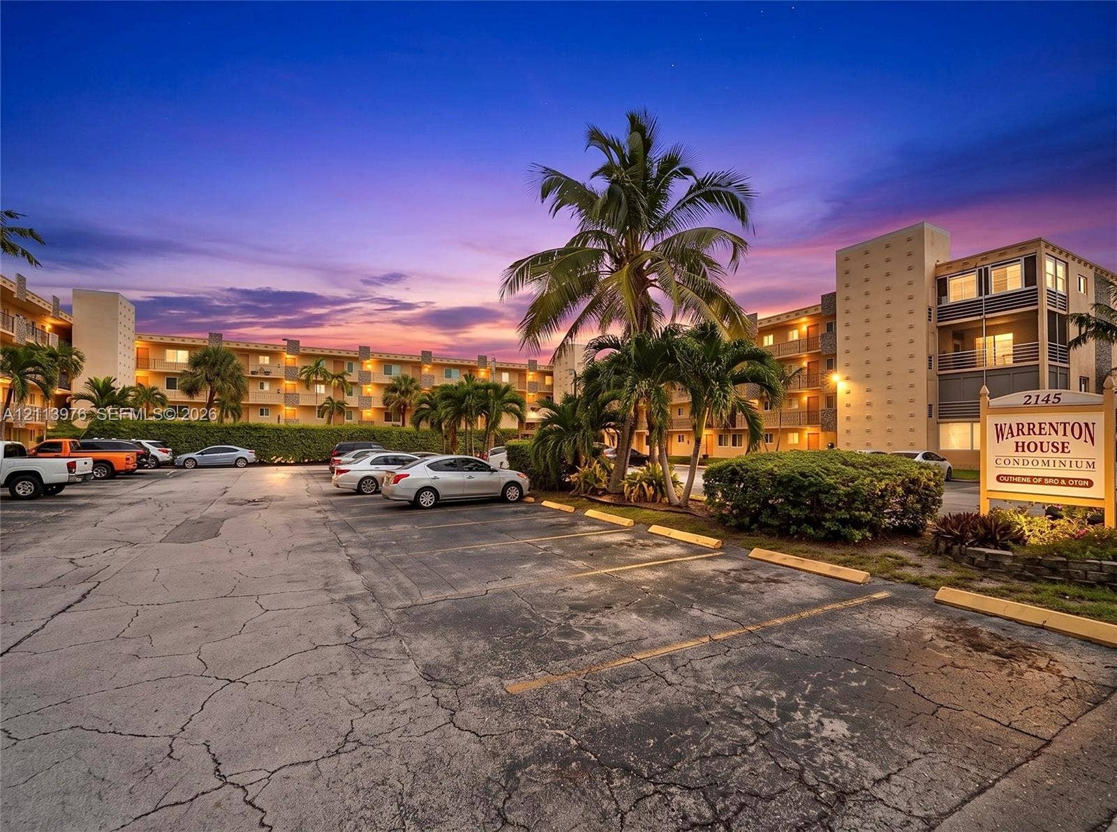 2145 Pierce Street, #416, Hollywood, FL 33020 Multi-story condominium exterior featuring an on-site parking area, structured balconies, and mature palm trees