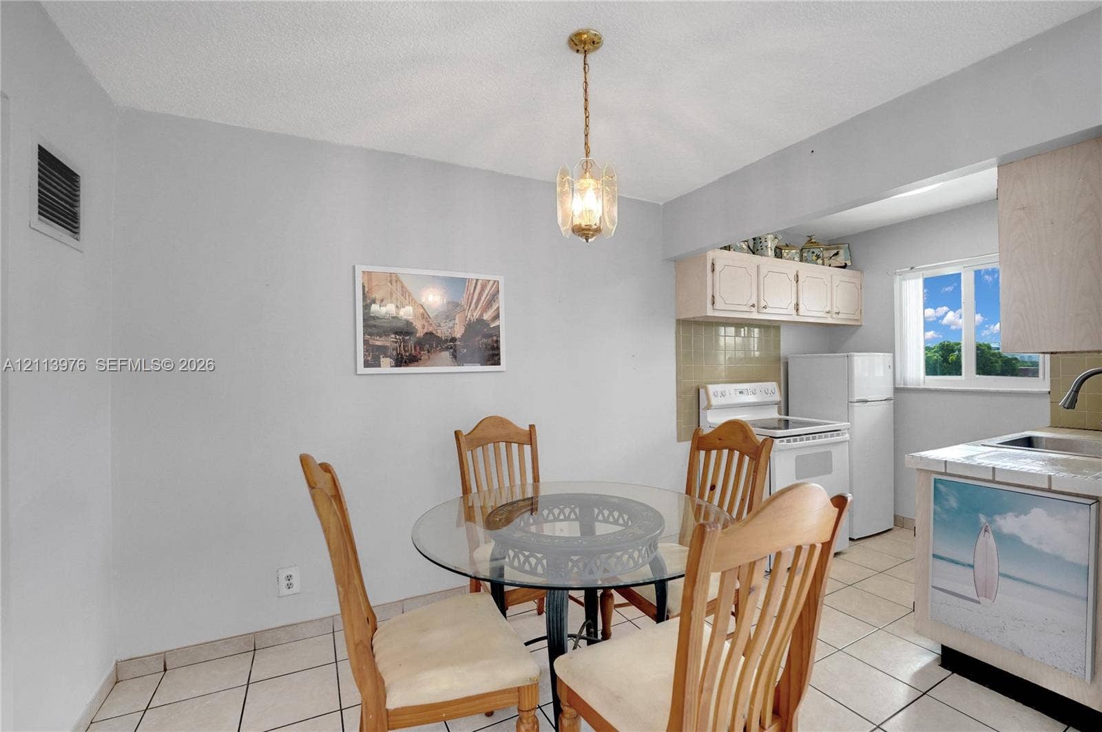 2145 Pierce Street, #416, Hollywood, FL 33020 Kitchen area featuring tile flooring, ceiling-mounted decorative pendant lighting, upper cabinetry, and a window