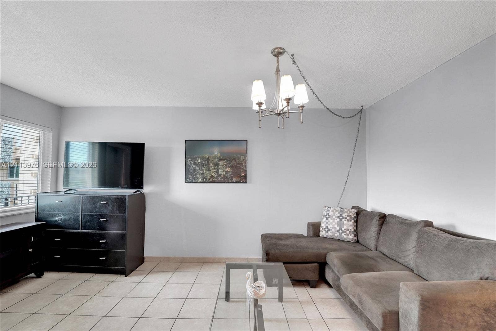 2145 Pierce Street, #416, Hollywood, FL 33020 Living area featuring neutral-toned tile flooring, multi-light chandelier, and large window with blinds
