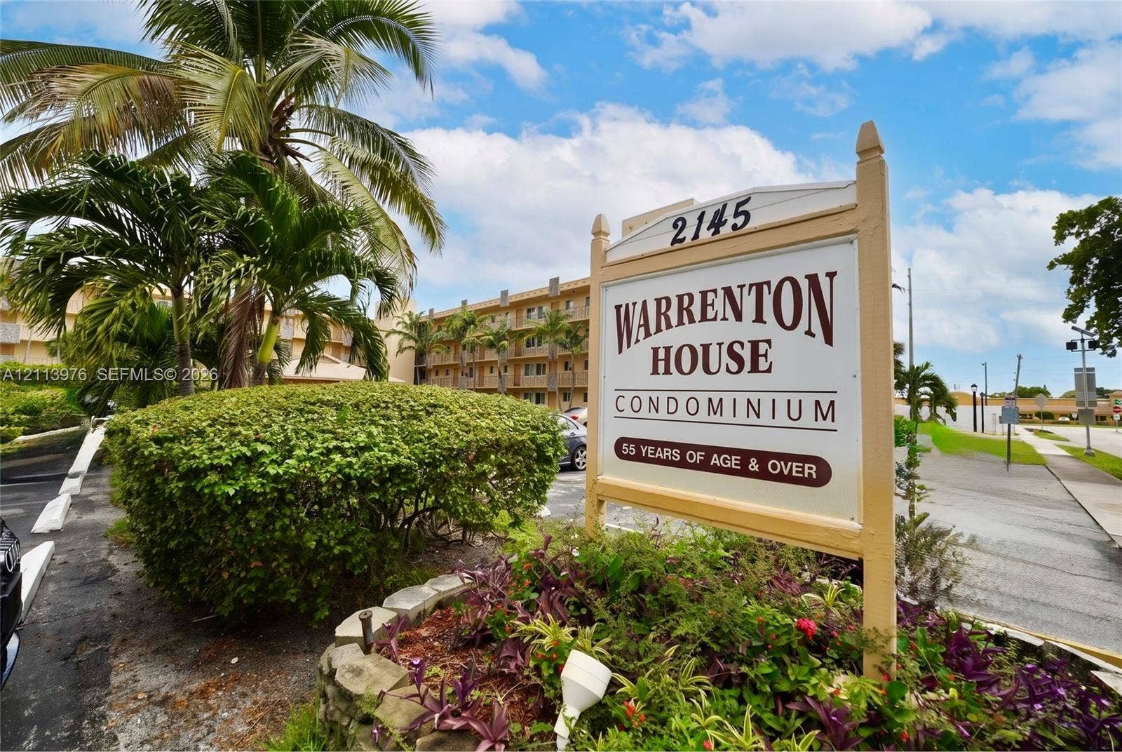 2145 Pierce Street, #416, Hollywood, FL 33020 Multi-story condominium exterior featuring exterior balconies, mature palm trees, and landscaped stone-bordered garden beds