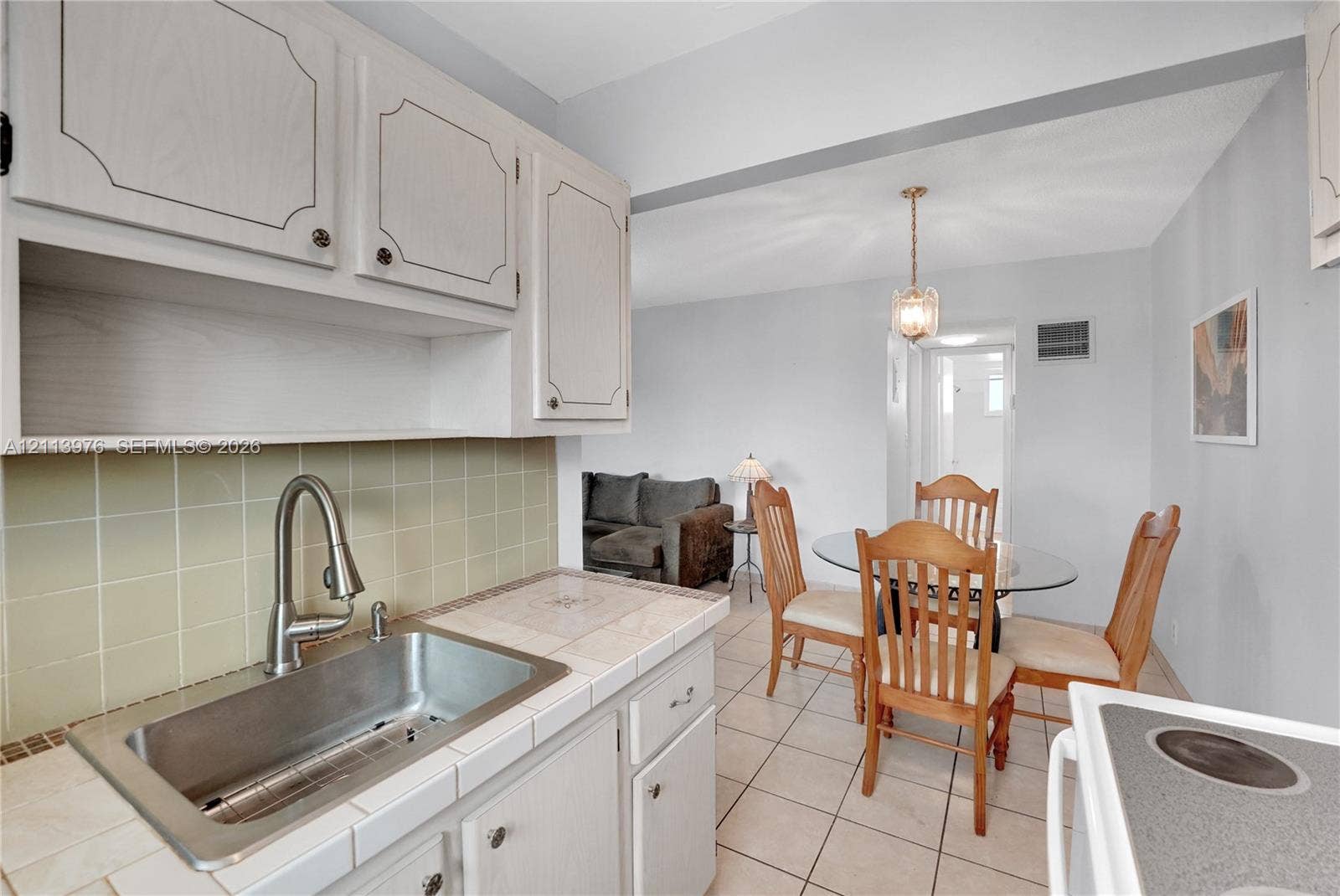 2145 Pierce Street, #416, Hollywood, FL 33020 Kitchen featuring light-toned cabinetry, tile countertops, stainless steel sink with high-arc faucet, and ceramic tile flooring