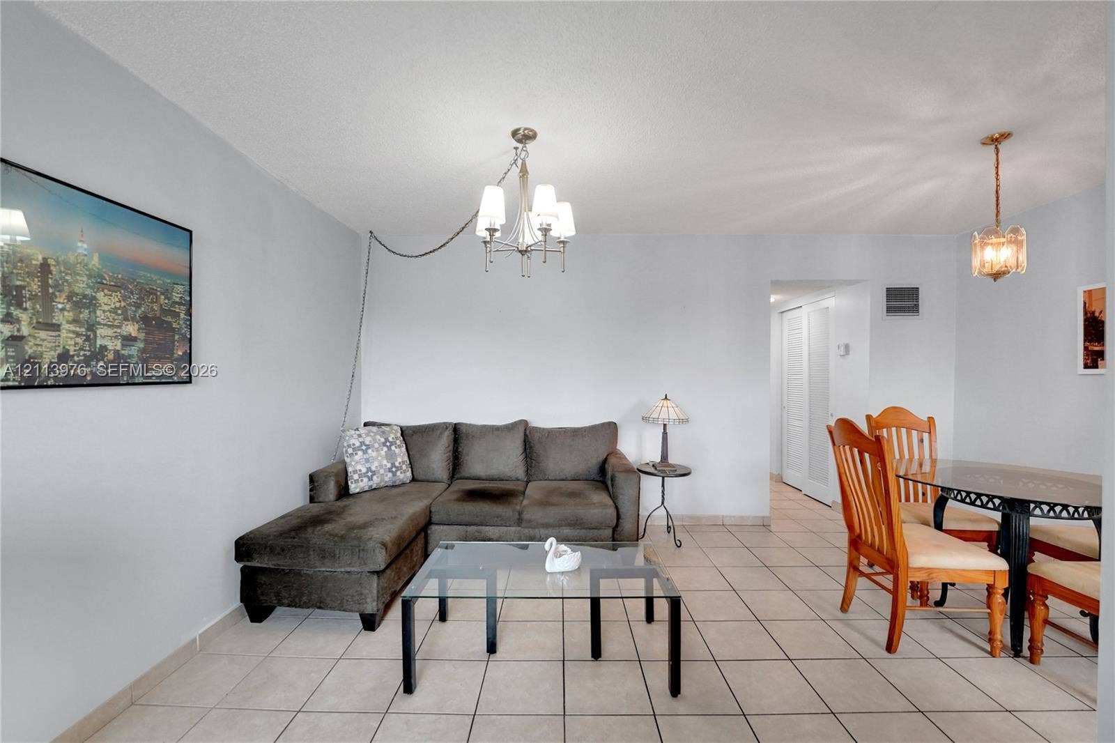 2145 Pierce Street, #416, Hollywood, FL 33020 Open-concept area featuring light-toned ceramic tile flooring, a multi-arm metallic chandelier, a decorative pendant light, and double-door closet access