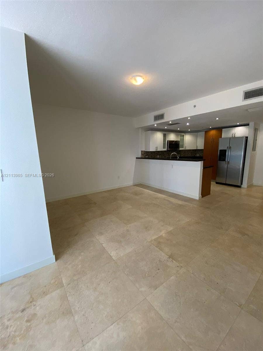 170 SE 14th Street, #2203, Miami, Miami, FL 33131 Large-format stone tile flooring, open kitchen peninsula with dark stone countertops, stainless steel refrigerator, and recessed ceiling lighting