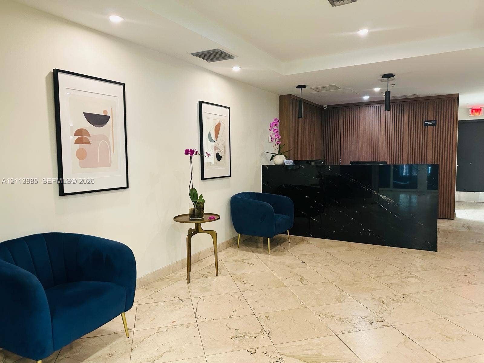 170 SE 14th Street, #2203, Miami, Miami, FL 33131 Lobby area featuring large-format stone flooring, a desk with a dark, polished stone front, vertical wood-slat wall paneling, and recessed ceiling lighting