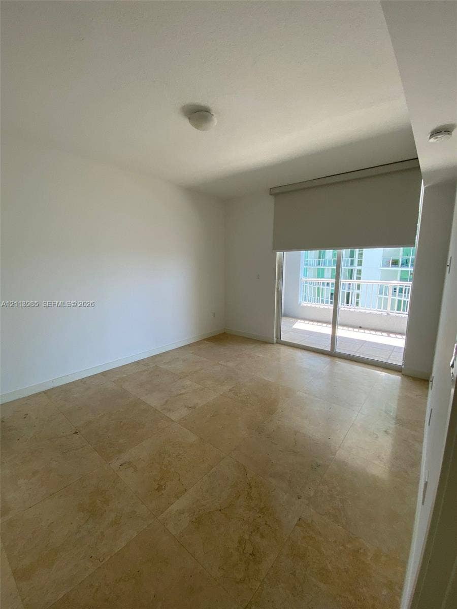 170 SE 14th Street, #2203, Miami, Miami, FL 33131 Neutral-toned natural stone flooring, sliding glass balcony door, and roller shade window treatment