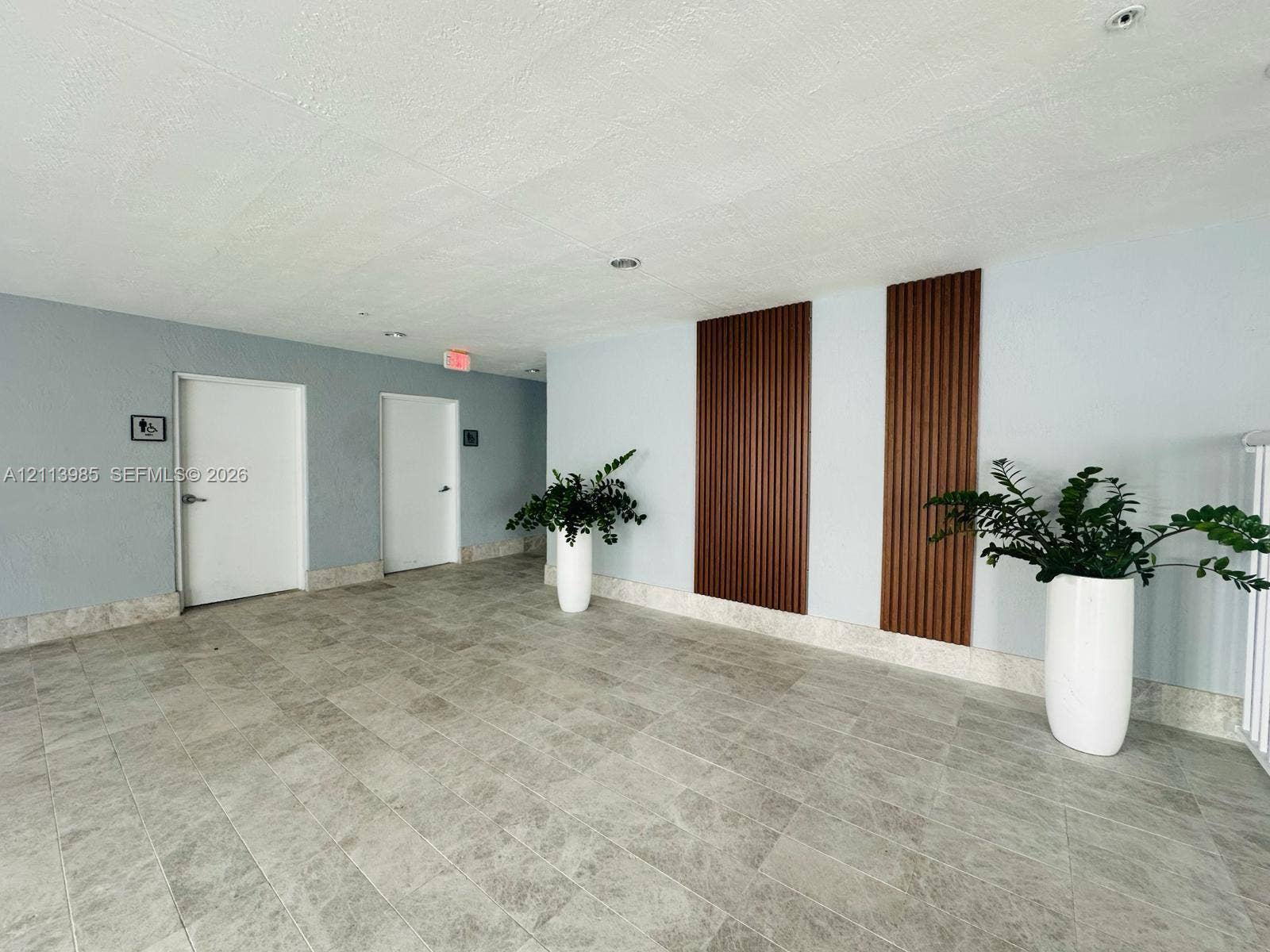 170 SE 14th Street, #2203, Miami, Miami, FL 33131 Interior hallway featuring neutral-toned tile flooring, vertical wood-slat wall paneling, and recessed ceiling lighting