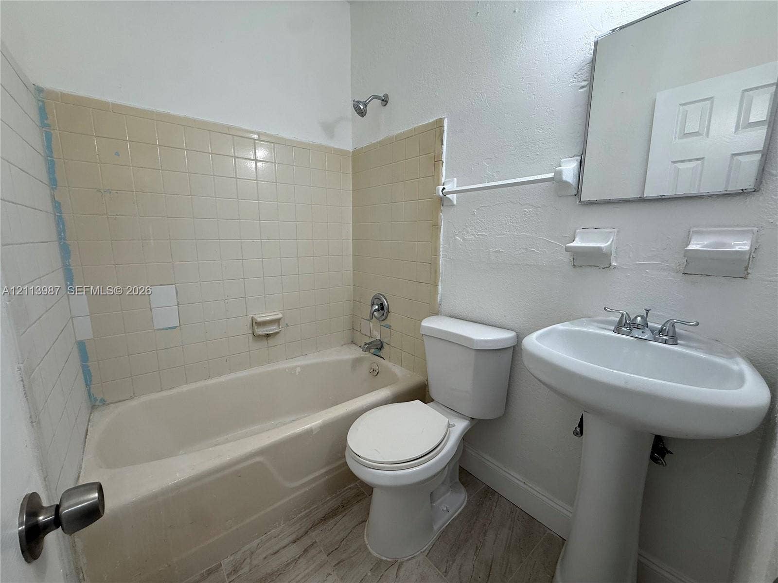 4428 Friden Drive, #4428, Jacksonville, Jacksonville, FL 32209 Bathroom featuring a pedestal sink, a bathtub with a tiled surround, a wall-mounted mirror, and wood-finish flooring