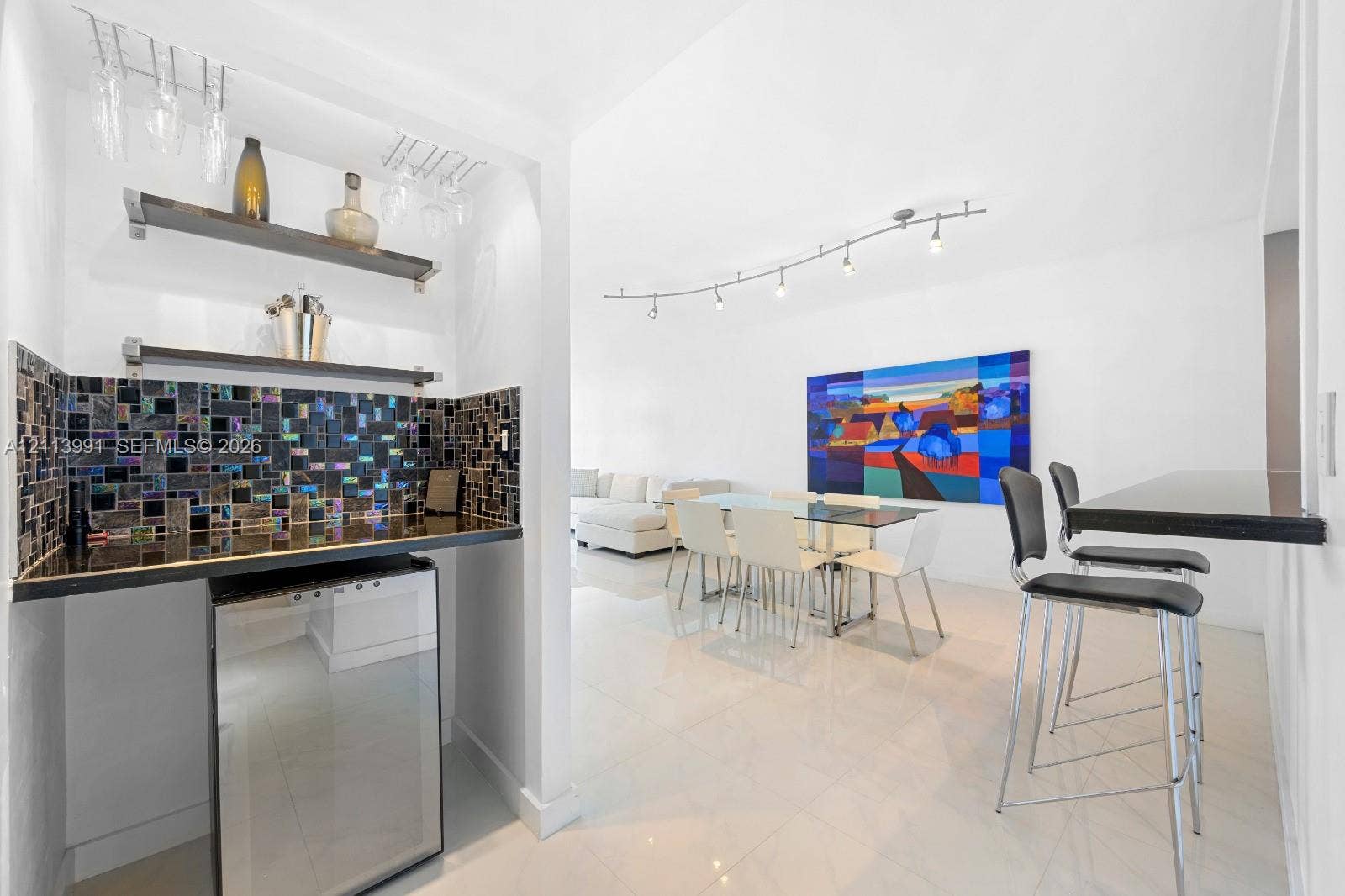 Built-in wet bar featuring a dark countertop, glass tile backsplash, and dual floating shelves