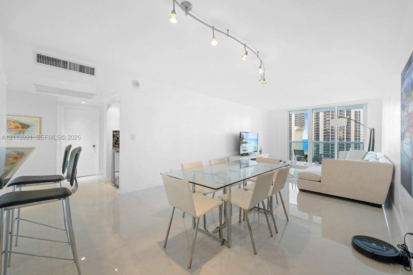 Open-concept area featuring polished tile flooring, track lighting, and floor-to-ceiling glass sliding doors