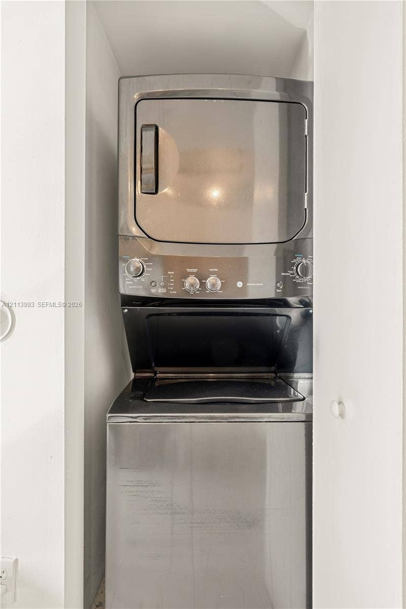 3180 SW 22nd Terrace, #407, Miami, Miami, FL 33145 Stacked metallic laundry unit featuring a top-mounted dryer and front-loading washing machine housed within a dedicated enclosure