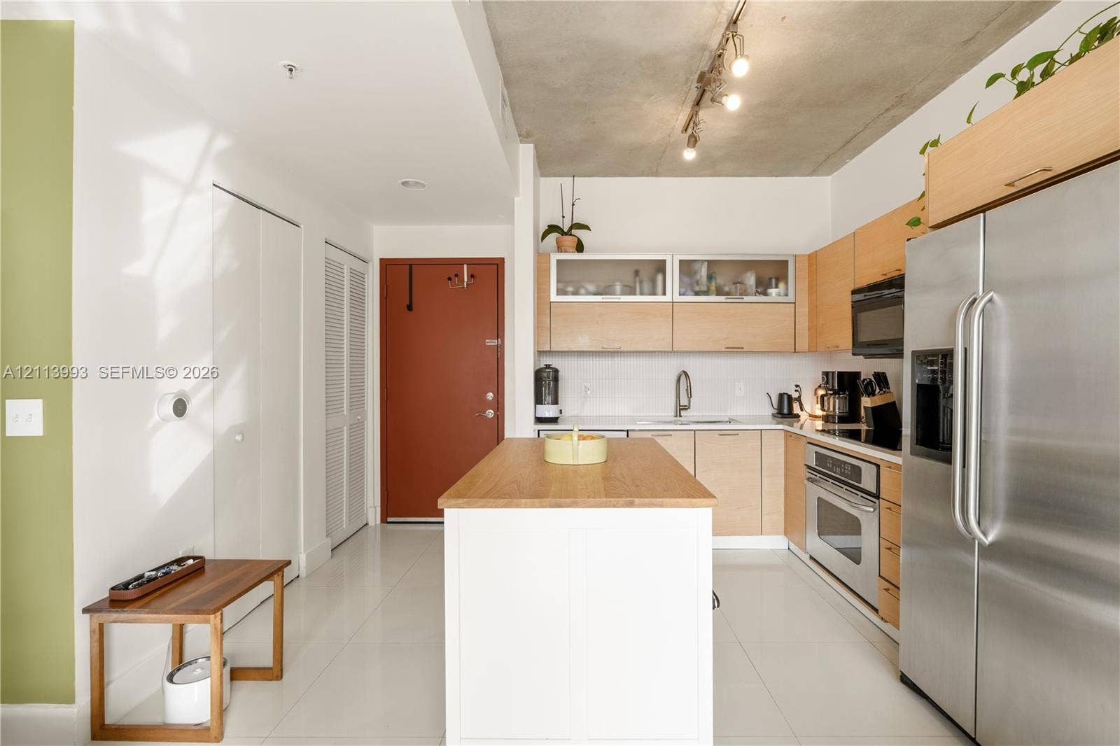 3180 SW 22nd Terrace, #407, Miami, Miami, FL 33145 Kitchen featuring light-finish cabinetry with glass-front uppers, a central island with a wood countertop, exposed concrete ceilings with track lighting, stainless steel appliances, and tile flooring