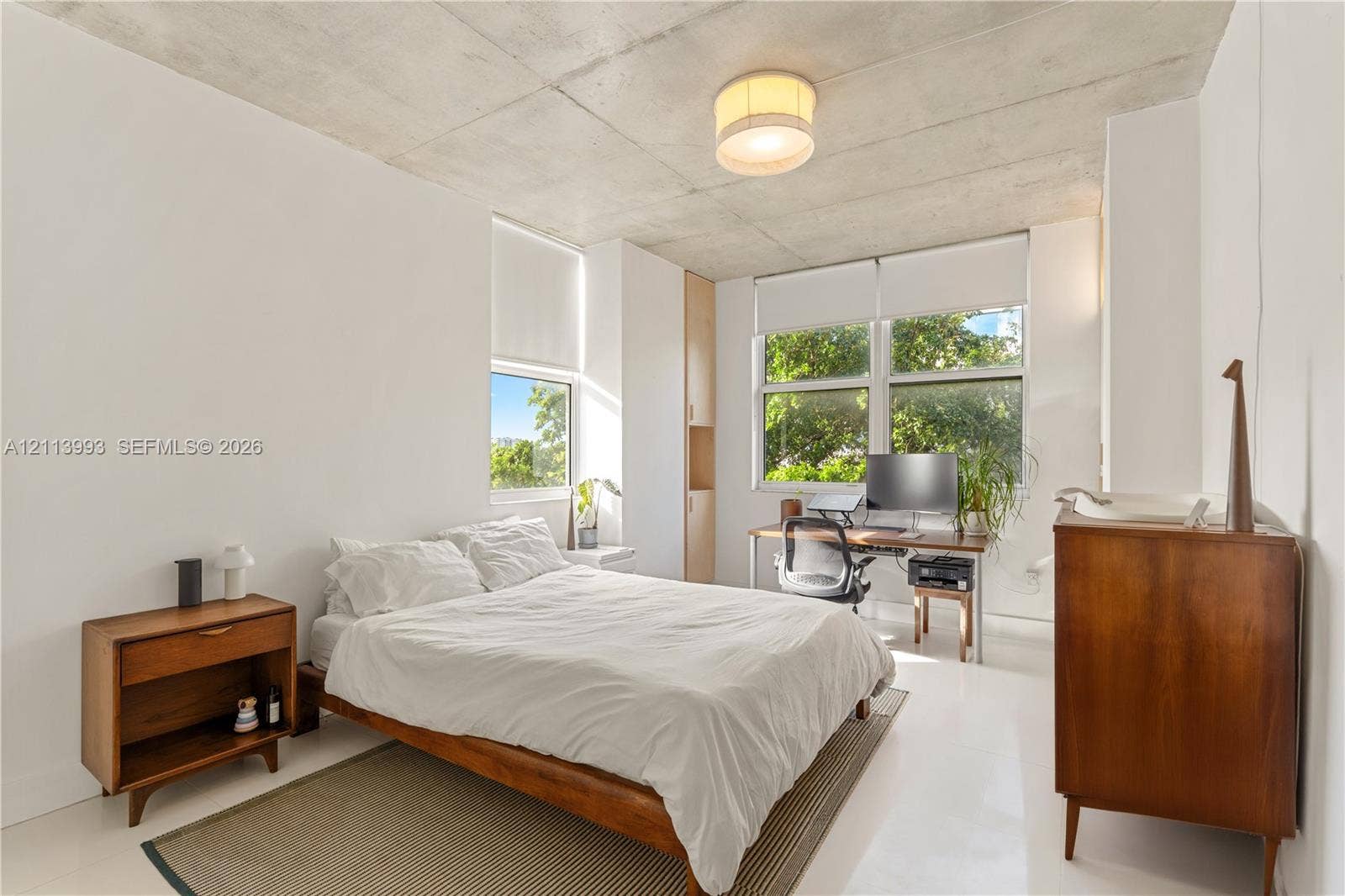 3180 SW 22nd Terrace, #407, Miami, Miami, FL 33145 Exposed concrete ceiling, large windows with neutral roller shades, glossy white flooring, and built-in floor-to-ceiling cabinetry