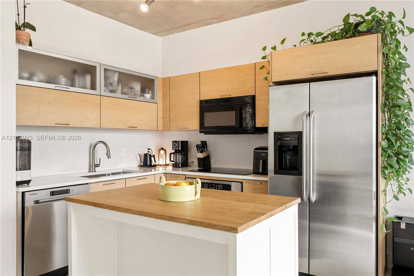 3180 SW 22nd Terrace, #407, Miami, Miami, FL 33145 Kitchen featuring light wood-finish flat-panel cabinetry with glass-front uppers, white backsplash tile, stainless steel appliances, and a center island with a wood-finish countertop