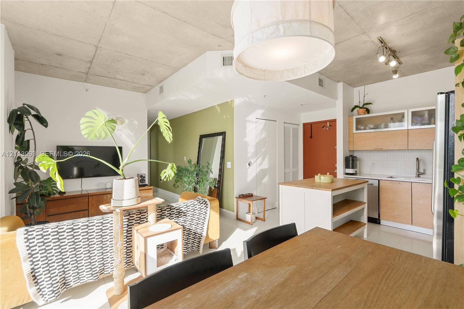3180 SW 22nd Terrace, #407, Miami, Miami, FL 33145 Exposed concrete ceiling, kitchen cabinetry with glass-front uppers, wood-finish base cabinetry, central kitchen island with wood-finish top, and drum pendant lighting
