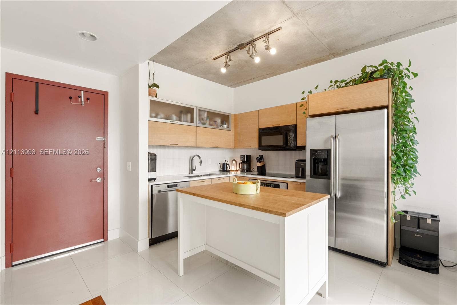 3180 SW 22nd Terrace, #407, Miami, Miami, FL 33145 Kitchen featuring light wood-finish cabinetry, white solid-surface countertops, industrial-style exposed concrete ceiling, stainless steel appliances, and a central prep island