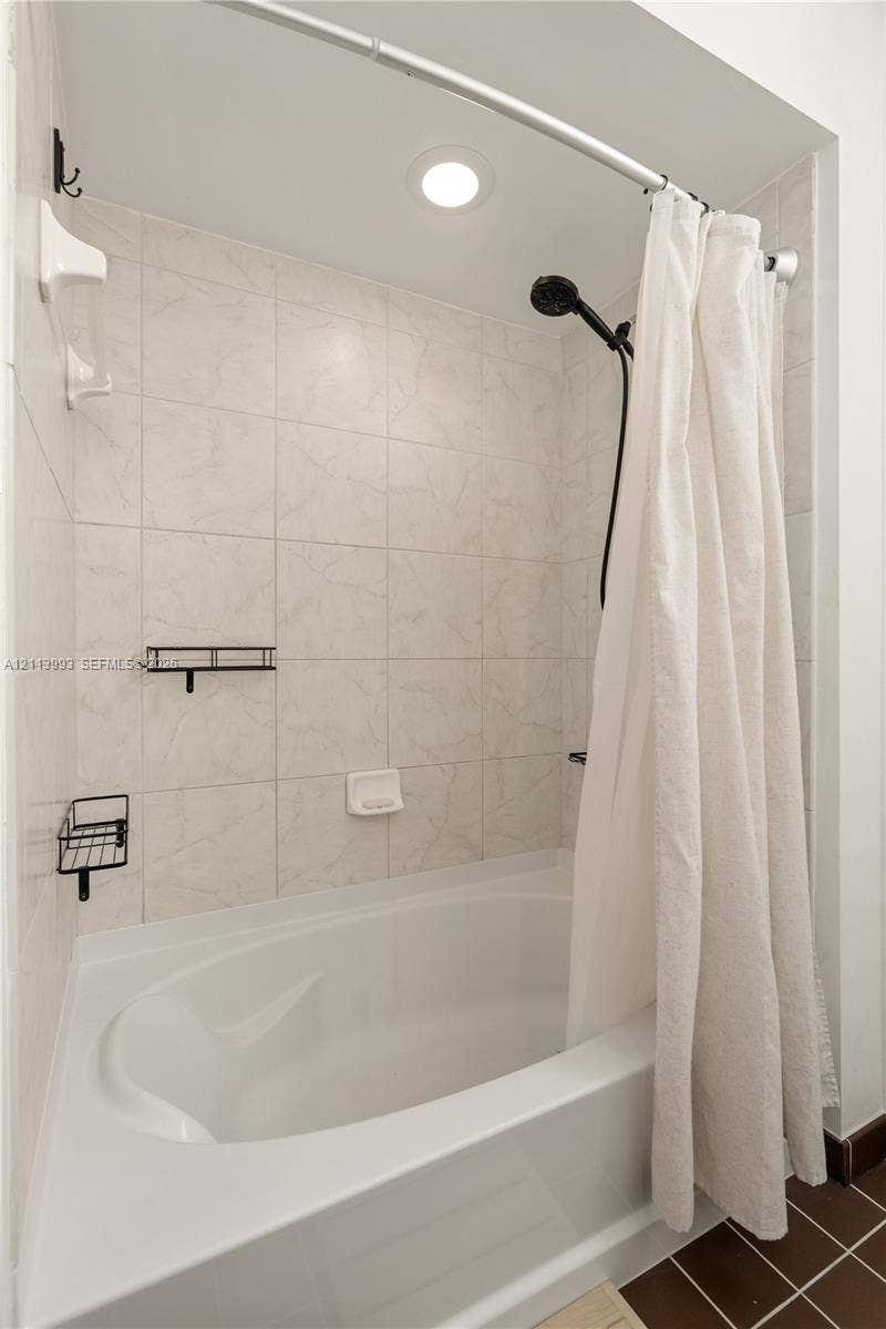 3180 SW 22nd Terrace, #407, Miami, Miami, FL 33145 Full-height shower enclosure featuring neutral stone-finish wall tile, an oval-shaped soaking tub, matte black shower hardware, and recessed lighting