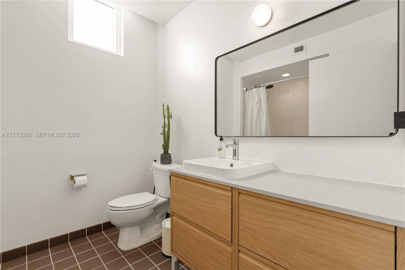 3180 SW 22nd Terrace, #407, Miami, Miami, FL 33145 Bathroom featuring a wood-finish vanity with an integrated basin, a large rectangular mirror with a black frame, and tiled flooring