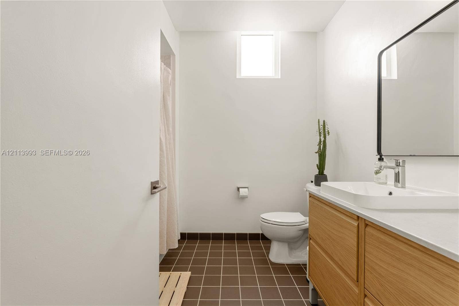 3180 SW 22nd Terrace, #407, Miami, Miami, FL 33145 Bathroom featuring a wood-finish vanity with a rectangular vessel sink, solid-surface countertop, rectangular mirror with a black frame, and brown tiled flooring