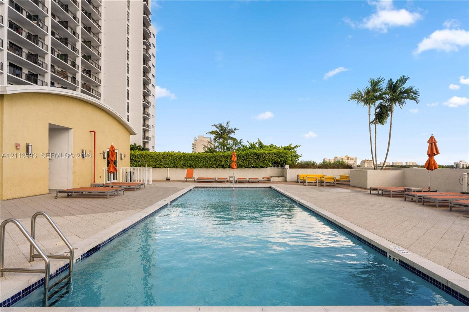 3180 SW 22nd Terrace, #407, Miami, Miami, FL 33145 Swimming pool with tiled decking, metal handrails, and a surrounding perimeter wall with greenery