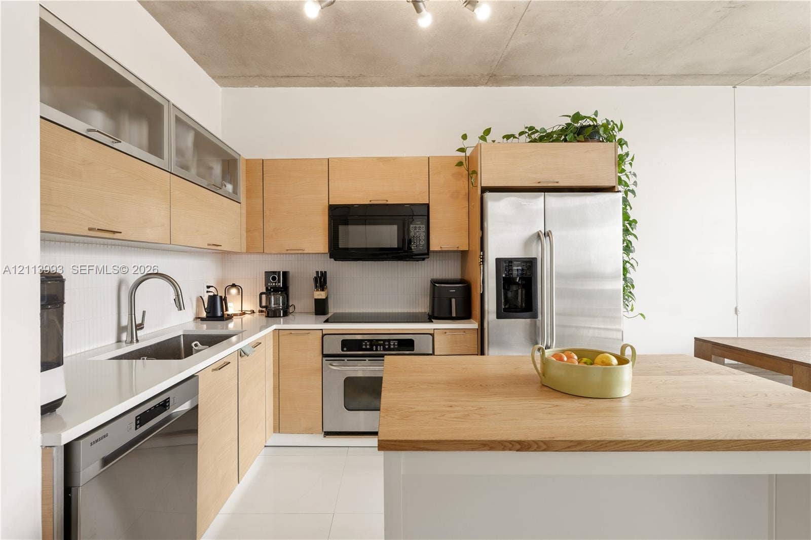 3180 SW 22nd Terrace, #407, Miami, Miami, FL 33145 Kitchen featuring flat-panel wood cabinetry, white stone-finish countertops, stainless steel appliances, a center island with a wood-finish surface, and an exposed concrete ceiling