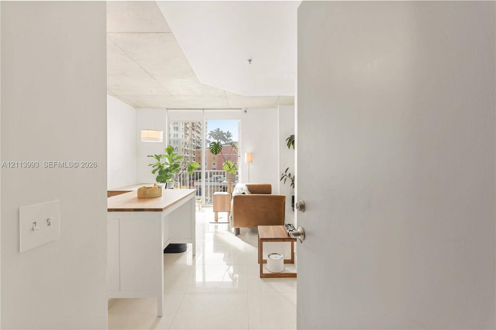 3180 SW 22nd Terrace, #407, Miami, Miami, FL 33145 Open-concept living space featuring high ceilings, polished tile flooring, and floor-to-ceiling glass sliding doors opening to a balcony
