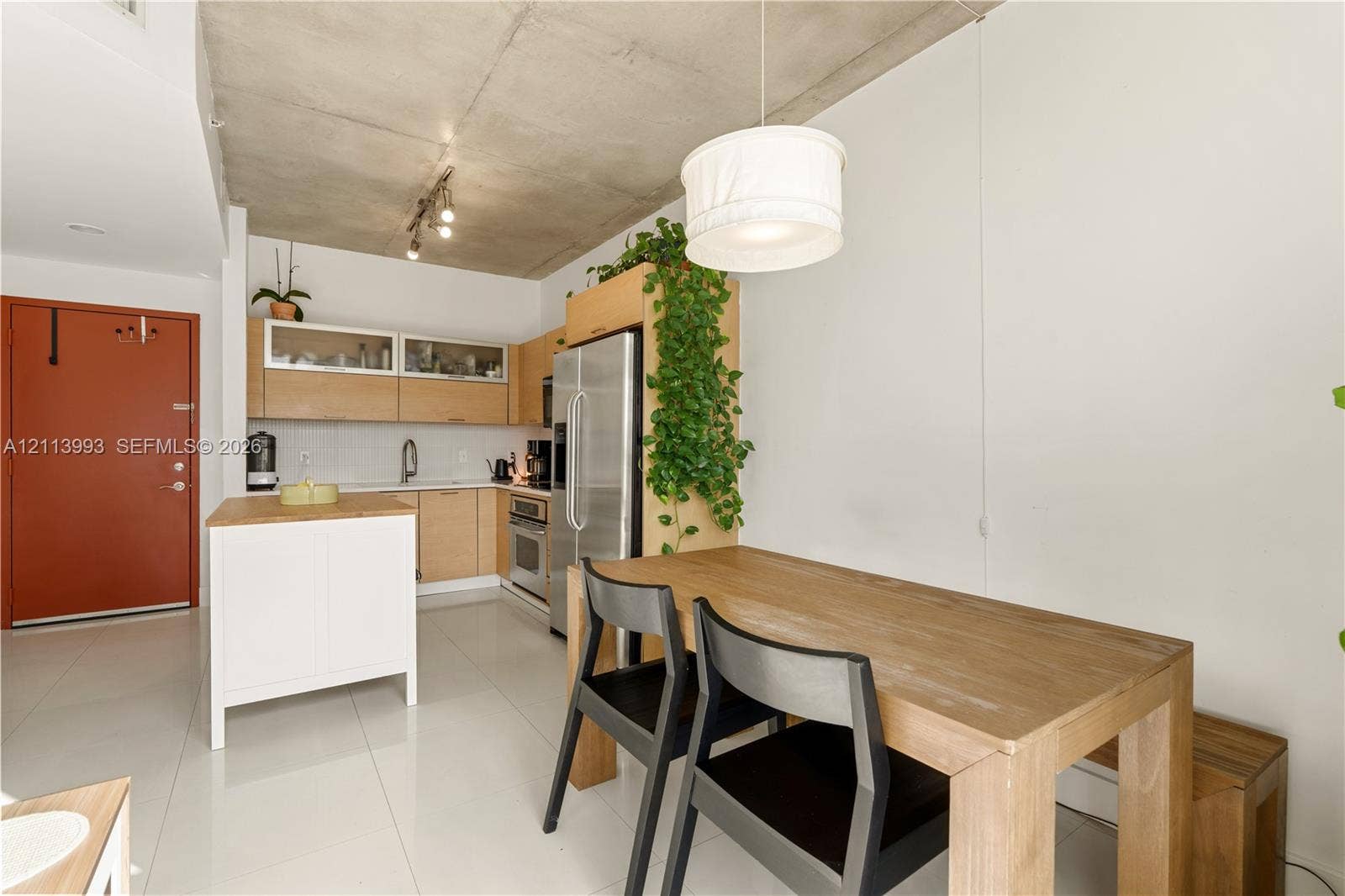 3180 SW 22nd Terrace, #407, Miami, Miami, FL 33145 Kitchen featuring exposed concrete ceiling, light wood cabinetry with glass-front uppers, stainless steel refrigerator, white portable island, and large-format tile flooring