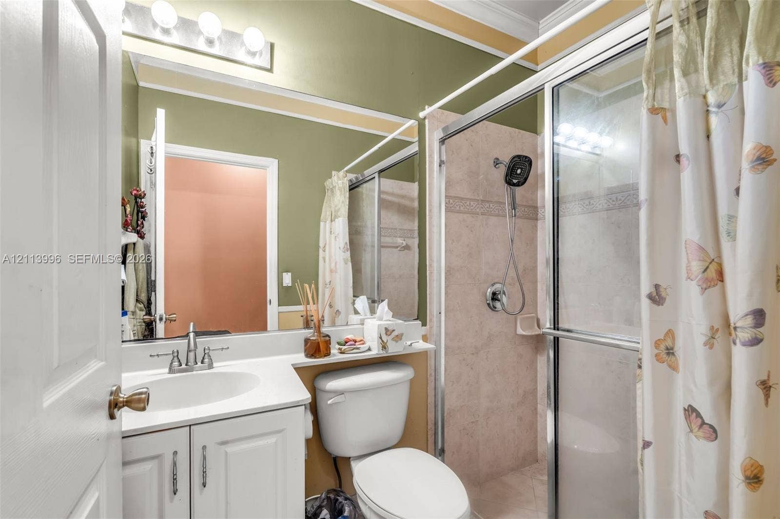 15503 SW 19th Street, Miramar, FL 33027 Bathroom featuring a white vanity with an integrated sink, polished chrome faucet, large vanity mirror with overhead lighting, and a glass-enclosed shower with tile surround