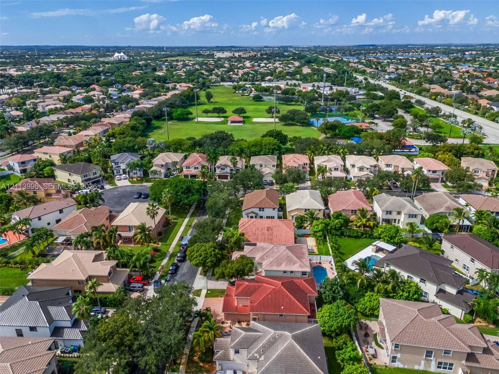 15503 SW 19th Street, Miramar, FL 33027 Aerial perspective of a suburban neighborhood featuring paved streets, mature landscaping, multi-story residences with tiled roofs, and an expansive recreational green space