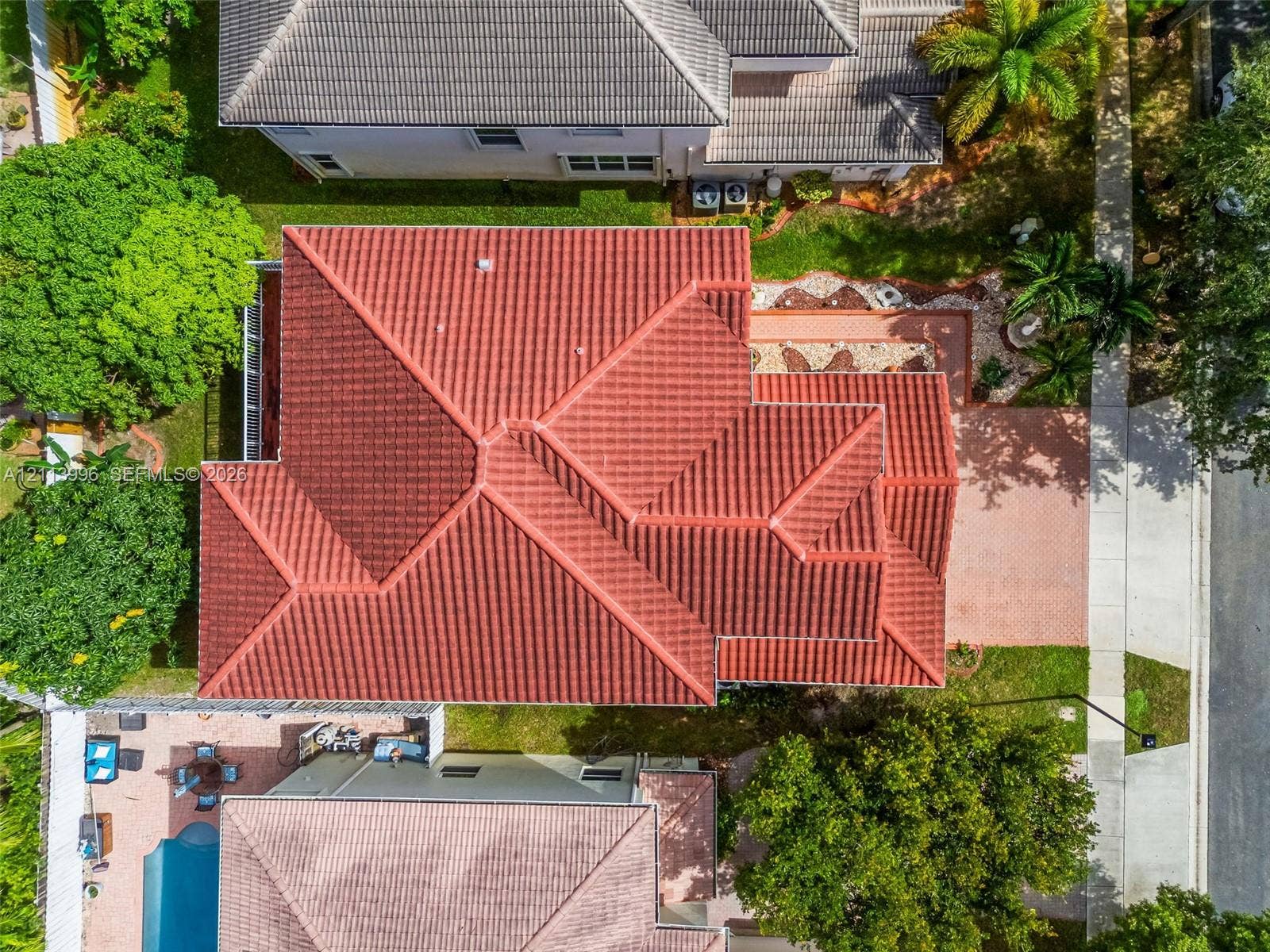 15503 SW 19th Street, Miramar, FL 33027 Aerial perspective of a multi-hip tile roof, expansive brick-paver driveway, and landscaped grounds featuring mature trees and established shrubbery