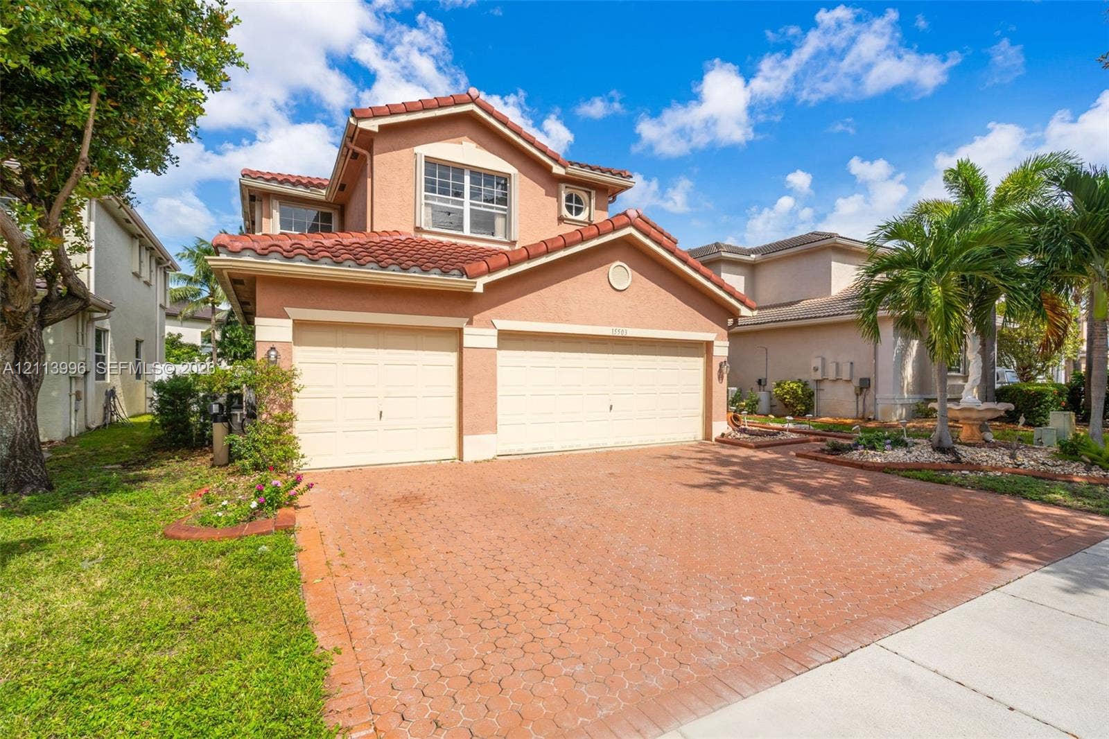 15503 SW 19th Street, Miramar, FL 33027 Stucco exterior featuring a terracotta tile roof, multi-car garage, and patterned paver driveway
