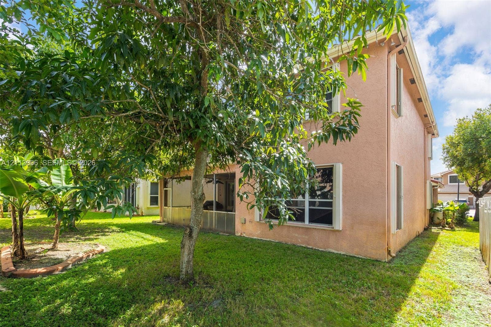 15503 SW 19th Street, Miramar, FL 33027 Stucco exterior featuring a screened-in rear porch and mature landscaping
