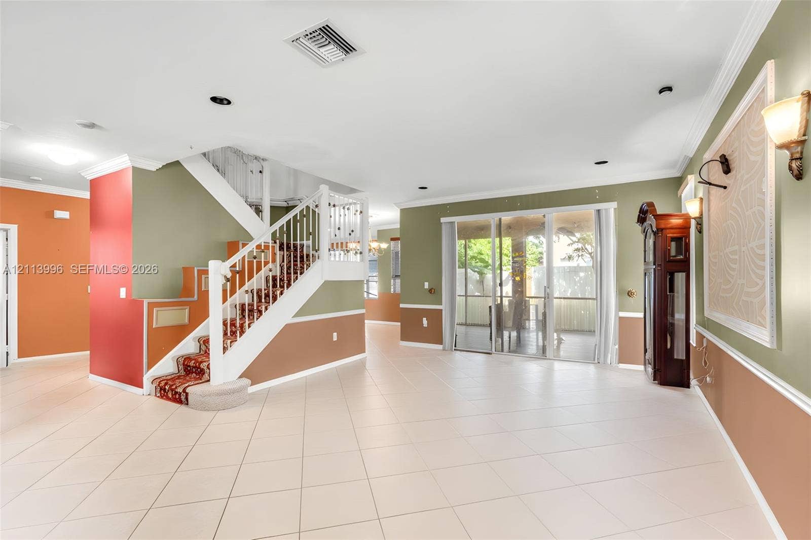 15503 SW 19th Street, Miramar, FL 33027 Open interior featuring ceramic tile flooring, a staircase with white balusters, sliding glass doors, and wall-mounted sconce lighting