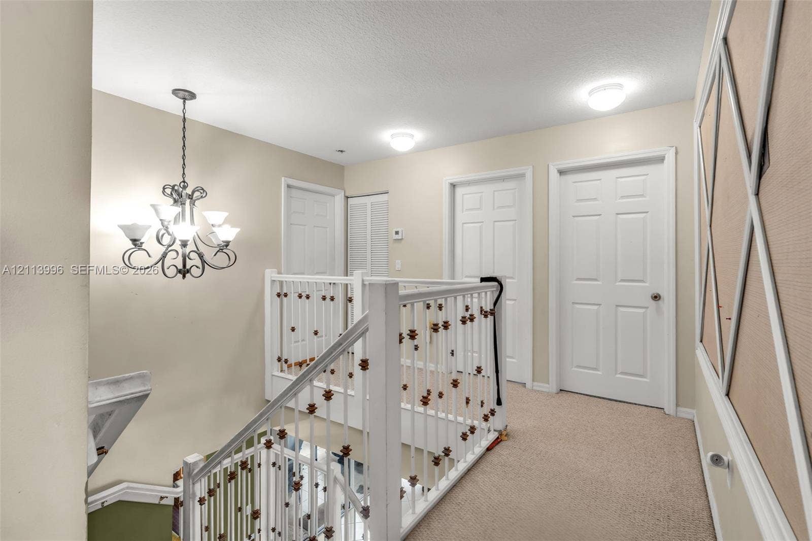 15503 SW 19th Street, Miramar, FL 33027 Traditional-style chandelier with scrolling metal arms, white six-panel interior doors, and railing featuring vertical balusters with decorative detailing