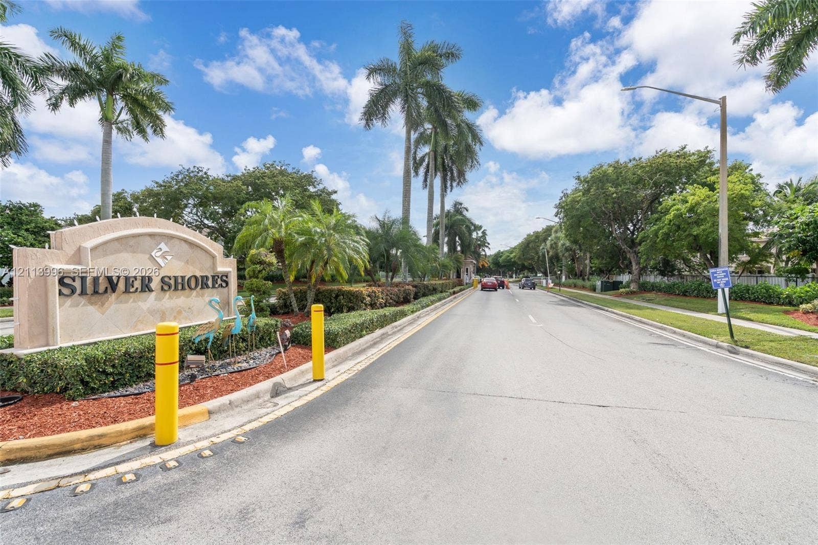 15503 SW 19th Street, Miramar, FL 33027 Community entrance monument featuring stone-finish masonry, mature palm trees, landscaped shrubbery, and paved roadway access