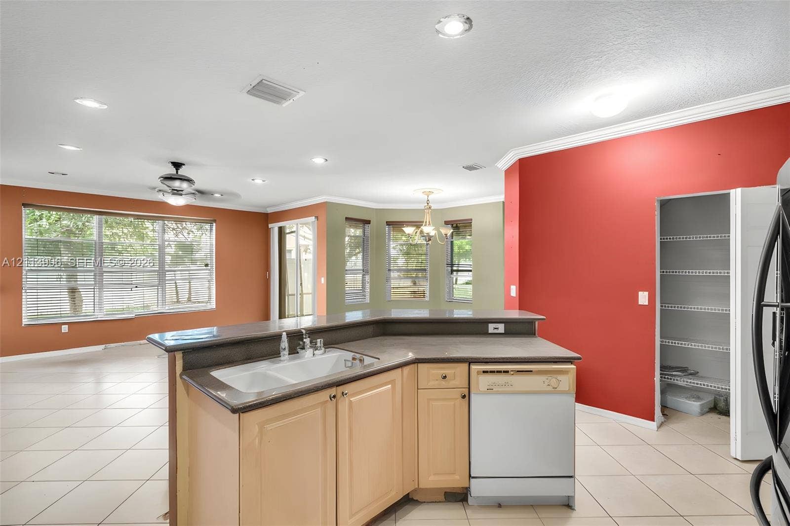 15503 SW 19th Street, Miramar, FL 33027 Kitchen island featuring a dual-basin sink, neutral-toned cabinetry, solid surface countertop, built-in dishwasher, and a walk-in pantry