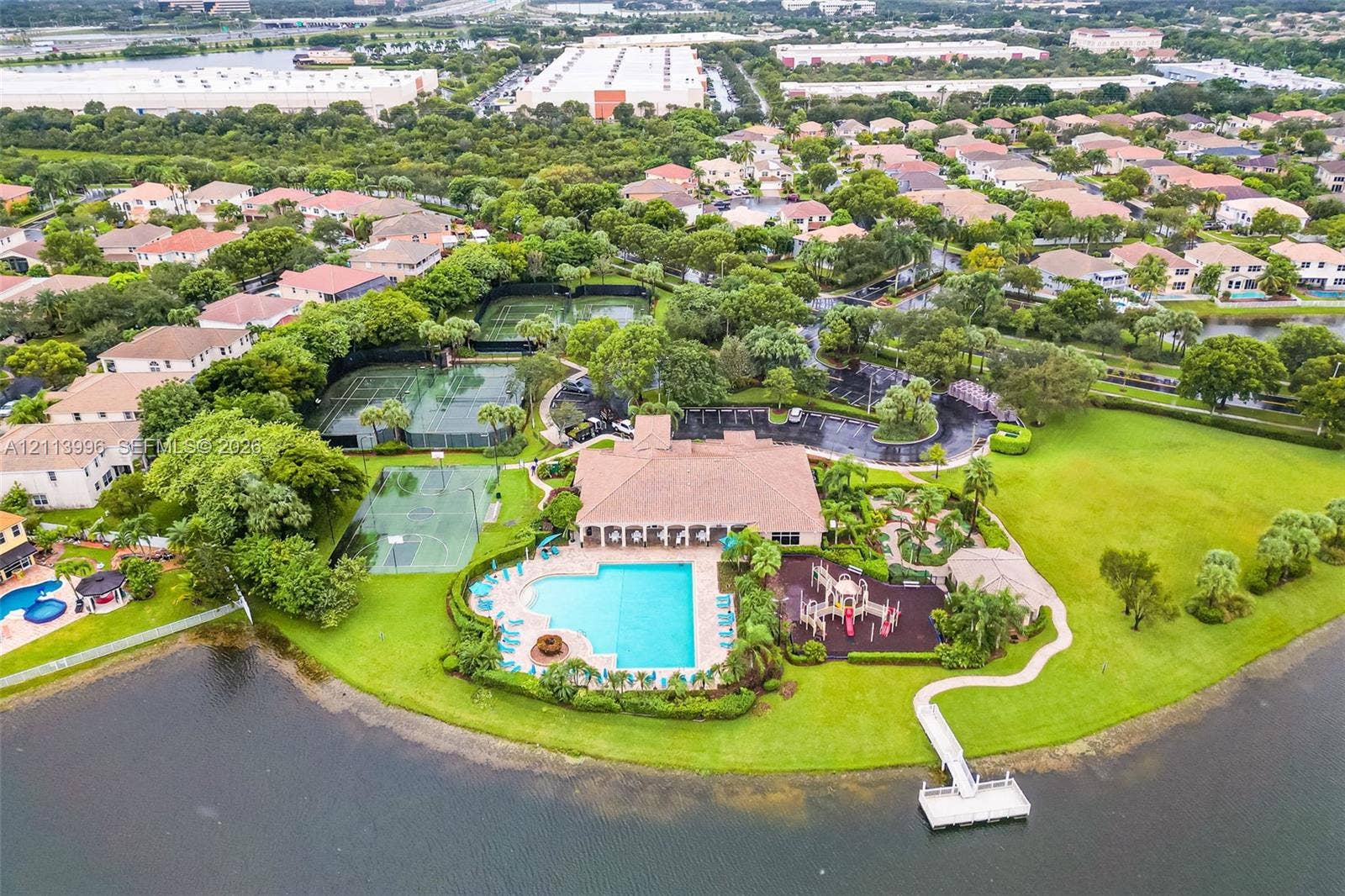 15503 SW 19th Street, Miramar, FL 33027 Aerial perspective of community clubhouse amenities featuring an outdoor swimming pool, tennis courts, playground equipment, and a private dock extending into the water