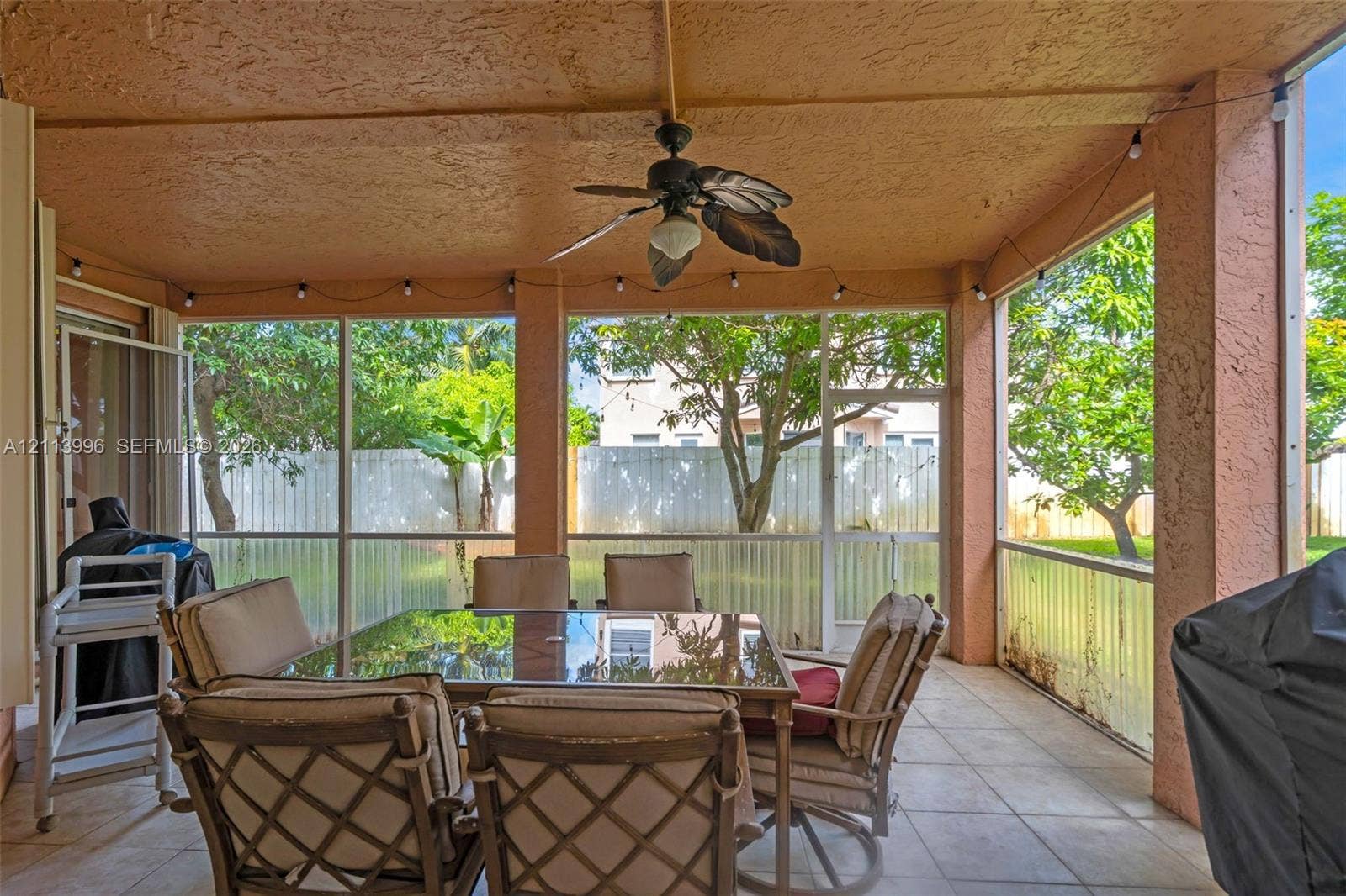 15503 SW 19th Street, Miramar, FL 33027 Screened-in covered patio featuring tile flooring, a ceiling fan, and string lighting