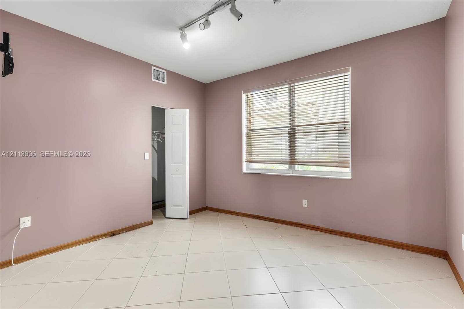 15503 SW 19th Street, Miramar, FL 33027 Room featuring neutral-toned walls, light-colored tile flooring, track lighting, and a closet with bifold doors