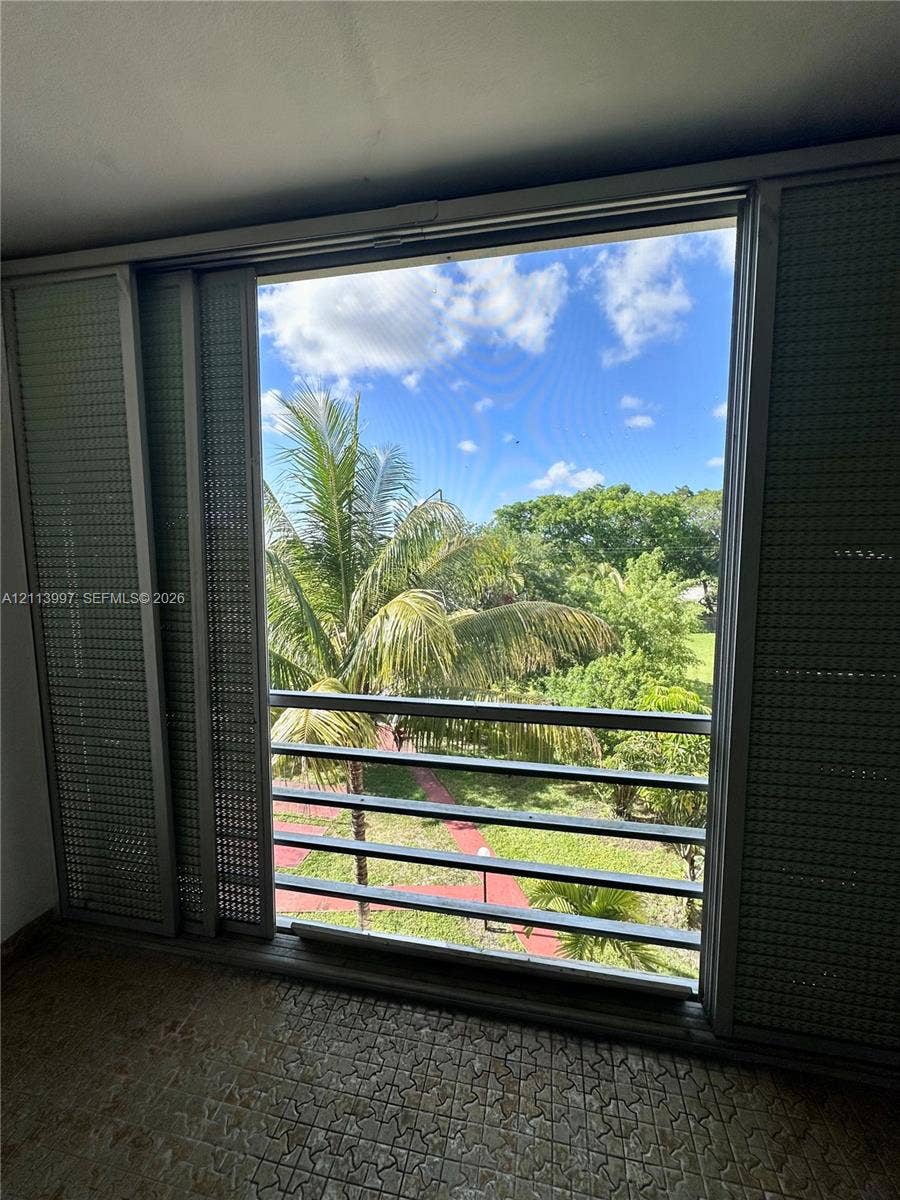 1501 NE 191st Street, #C412, Miami, FL 33179 Large window featuring floor-to-ceiling sliding metal shutters, horizontal metal balcony railings, and exterior natural scenery