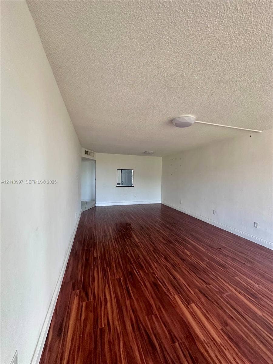 1501 NE 191st Street, #C412, Miami, FL 33179 Interior space featuring wood-finish flooring, white walls, a flush-mount ceiling light fixture, and an interior pass-through window