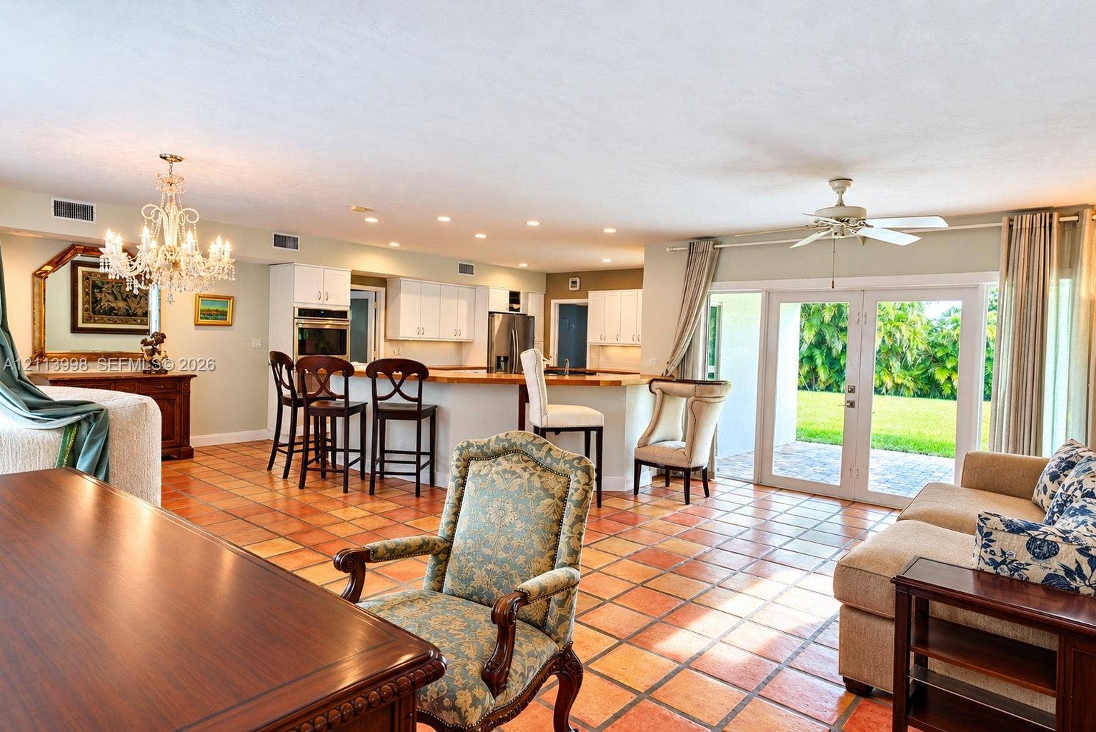 16455 SW 91st Avenue, Palmetto Bay, FL 33157 Open-concept kitchen and living area featuring ceramic tile flooring, built-in wall oven, multi-level breakfast bar, and glass-paneled double doors providing outdoor access